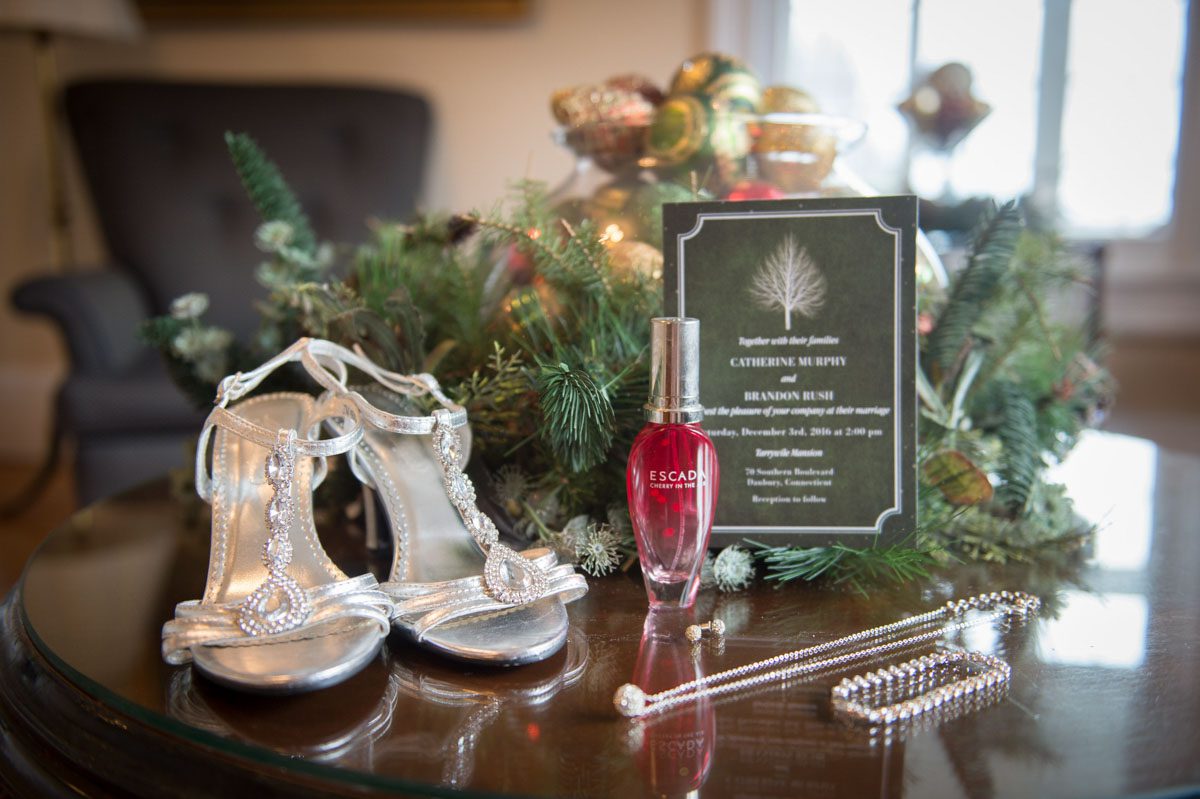 A December Wedding shoes, perfume, invitation and jewelry on table with decorations